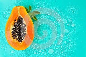 Papaya fruit on blue background with water drops, fresh exotic fruits border design. Half of fresh organic Papaya