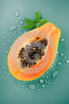Papaya fruit on blue background with water drops, fresh exotic fruits design. Half of fresh organic ripe Papaya
