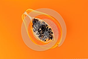 Papaya fruit on orange, yellow background. Half of fresh organic Papaya exotic fruit close up. Top view