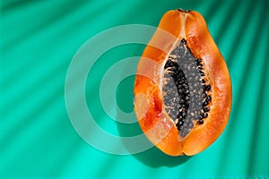 Papaya fruit on tropical green background with shadows of palm tree. Halved fresh organic Papaya exotic fruit