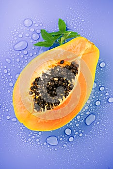 Papaya fruit on violet bright background with water drops, fresh exotic fruits design. Half of fresh organic ripe Papaya