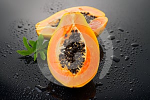 Papaya fruit on wet black background with water drops. Halved fresh organic Papaya exotic fruits