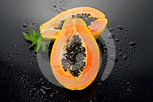 Papaya fruit on wet black background with water drops. Halved fresh organic Papaya exotic fruits