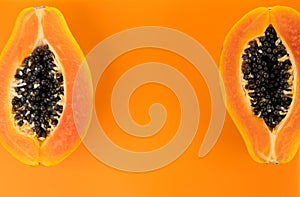 Papaya fruits on orange, yellow background. Halved fresh organic Papaya exotic fruit border design