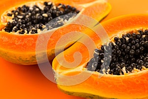 Papaya fruits on orange, yellow background. Halved fresh organic Papaya exotic fruit design, close up