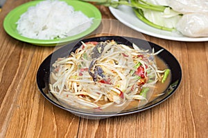 Papaya salad in black plate on wooden board