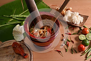 Papaya salad ingredients are mixing and pounding in a mortar.