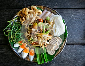 A papaya salad and mixed refreshing vegetables with boiled eggs on the black dish photo taken from the top view. Thailand local fo