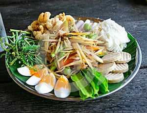 A papaya salad and mixed refreshing vegetables with boiled eggs on the black dish photo taken from the top view. Thailand local