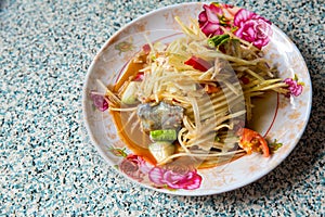Papaya salad, which put Pickled Fish and long beans. Papaya salad in white dish on wooden background.
