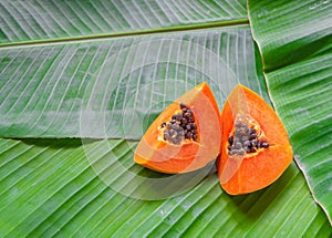 Papaya slices on banana leaves. Tropical summer background with copy space