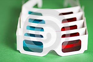 Paper 3d glasses in row on green background. Watching the movie in the cinema concept. The film is in 3D.