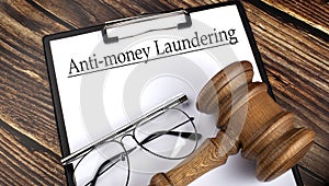 Paper with Anti-money laundering AML with gavel, pen and glasses on wooden background