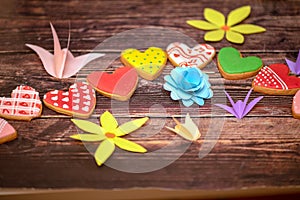 Paper art, bright summer holiday handmade flowers, craft on a wooden background with cookies in the form of hearts