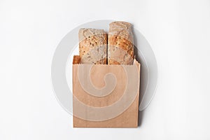 Paper bag with bread loaves on white background, top view.