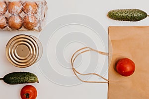 Paper bag with cucumbers, tomatoes, vegetable oil, eggs and canned goods isolated on white background.Food supplies crisis food