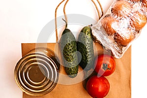 Paper bag with cucumbers, tomatoes, vegetable oil, eggs and canned goods  on white background.Food supplies crisis food