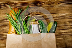 Paper bag with different food on wooden table. Top view. Grocery shopping concept