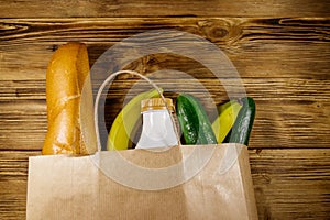 Paper bag with different food on wooden table. Top view. Grocery shopping concept