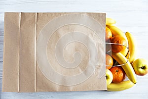 Paper bag of different fruits on white wooden