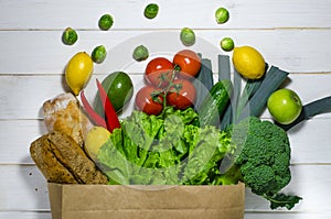 Paper bag of different health food on white wooden background