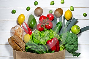 Paper bag of different health food on white wooden background