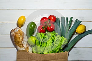 Paper bag of different health food on white wooden background. Top view