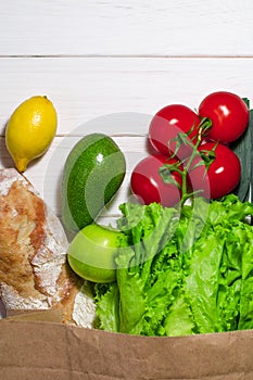 Paper bag of different health food on white wooden background. Top view