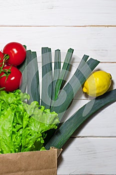 Paper bag of different health food on white wooden background. Top view