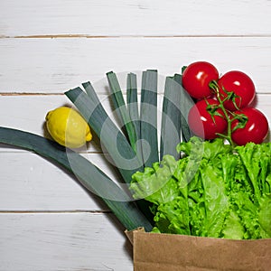 Paper bag of different health food on white wooden background. Top view