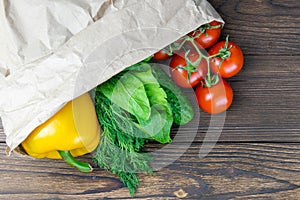 Paper bag of different health vegetables on a black wooden background. Top view. Flat lay