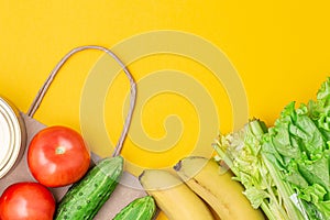 Paper bag with food, canned food, tomatoes, cucumbers, bananas, lettuce on a yellow background