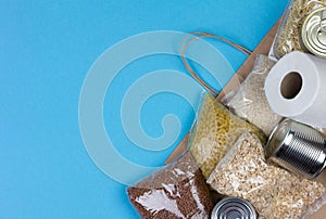 Paper bag with a food supply for the period of quarantine isolation of coronavirus for people in need rice, pasta, oatmeal, canned