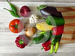 Paper bag full of juicy organic green red peppers, red tomato, purple eggplant, yellow onion, white garlic and maize. Summer.