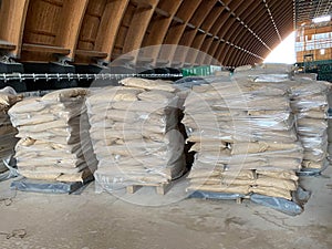 Paper bags of cement in dirty polyethylene lie on a wooden euro pallet. Building materials for the construction of the sidewalk.