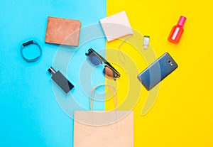 Paper bags and many purchases of gadgets and accessories on a colored background: sunglasses, smartphone, smart bracelet