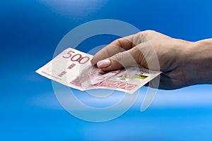 paper banknote in hand on a blue background. 500 Swedish krona. payment for the purchase