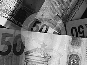 Paper banknotes in denominations of 50 dollars and 50 euros, a close-up shot. Black and white image