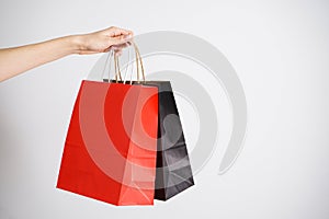 Paper black and red bag, eco packaging in a female hand on a white background. Space for text