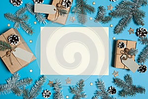 Paper blank, boxes with gifts, fir branches, pine cones, wooden decorative stars on a light blue background. Christmas, winter, Ne