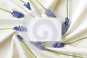 Paper blank in frame of blue spring flowers. Flat lay. Close-up. Copy space for inspirational texts, beautiful quotes or