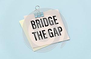 Paper on the blue background with text Bridge The Gap