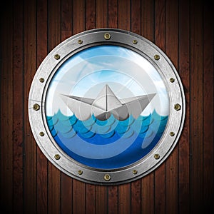 Paper boat in the blue waves of the sea seen through the porthole