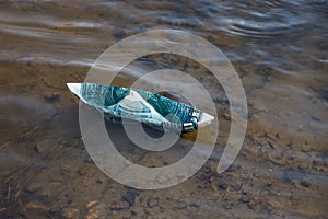 A paper boat of a dollar bill ran aground. Symbolic image