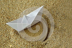 Paper boat and euro coin on the sand - Concept of immigration