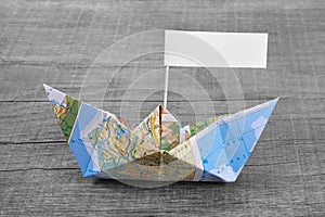 Paper boat folded out of a map with a time-out sign on an grey w