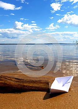 A paper boat on the river bank and a curious snake