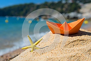 Paper boat and starfish at the beach