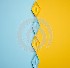 Paper boats on a yellow background, top view, representing the concept of unity and achieving common goals