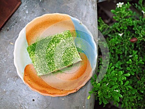 A paper bowl of trendy Taiwanese dessert; taro ball, potato ball with grass jelly and scoop of ice cream over shaved ice.